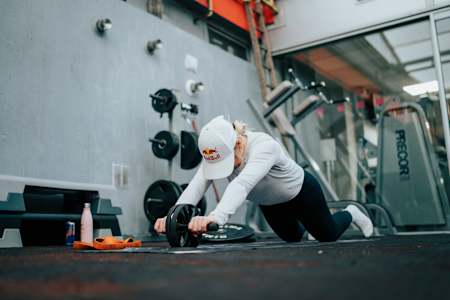 La championne de ski freestyle Tess Ledeux fait du gainage avec une roue abdominale pendant une séance d'entraînement fitness.