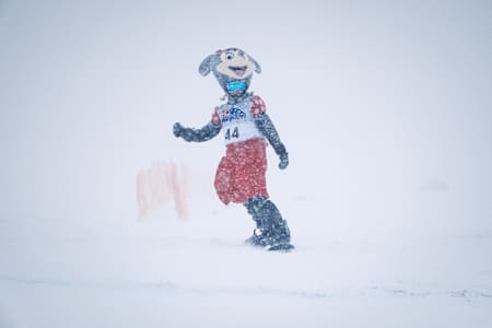 I 2024 løper en utkledd maskot med nummer 44 gjennom tung snø på Red Bull Homerun-arrangementet i Stranda, Norge.  