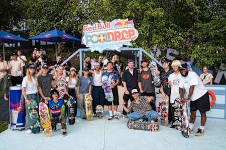 Beim Red Bull Pool Drop-Event posiert eine lebhafte Gruppe von Skateboardern, darunter Angelo Caro, Leticia Bufoni und andere, mit ihren Boards und dem Red Bull-Branding