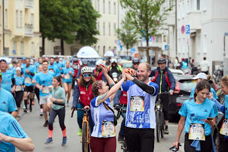 Stimmung? Ja! Diese beiden Teilnehmer:innen klatschen sich beim Wings for Life World Run Flagship Run in München ab. 