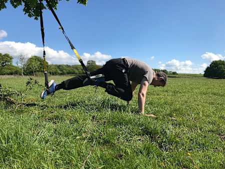 How to perform single-leg knee tuck using a TRX