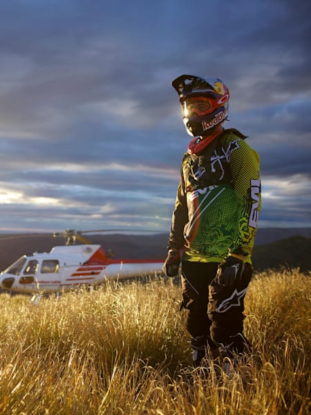 Rider Brook MacDonald stojący na szczycie góry Remarkables w Nowej Zelandii po dotarciu na szczyt helikopterem.