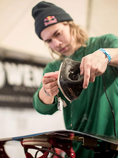 Snowboardzista Roope Tonteri smaruje swoją deskę snowboardową.
