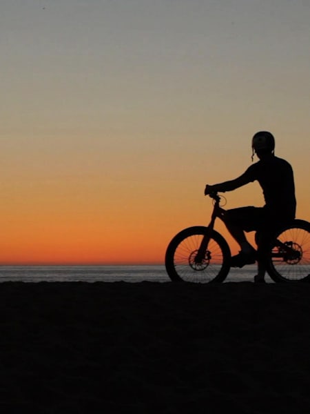 Danny MacAskill sobre su MTB, mirando el atardecer.