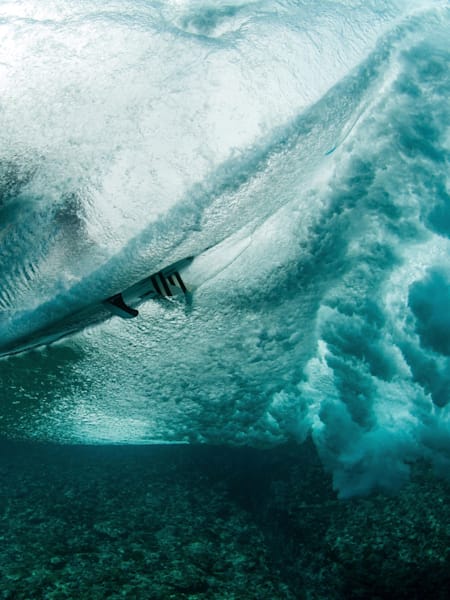 A surfer is photographed from underwater at Teahupoo, Tahiti