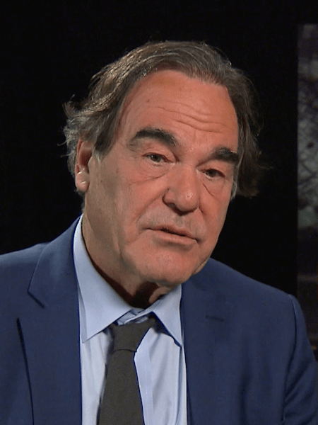 Director Oliver Stone with a film poster for Snowden in the background