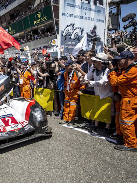 Hartley and Bamber of New Zealand celebrate on the roof of the #2 Porsche LMP1 919 Hybrid driven by Timo Bernhard of Germany on the way to the prize giving ceremony during the 24 Hours of Le Mans.