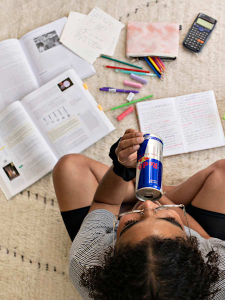 Un étudiant étudie et boit une canette de Red Bull