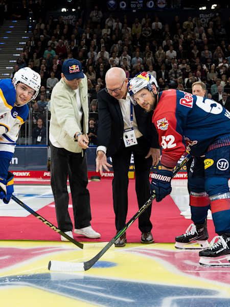 Zwei Spieler liefern sich ein Bully in einem Spiel der National Hockey League, während der Schiedsrichter den Puck einwirft.