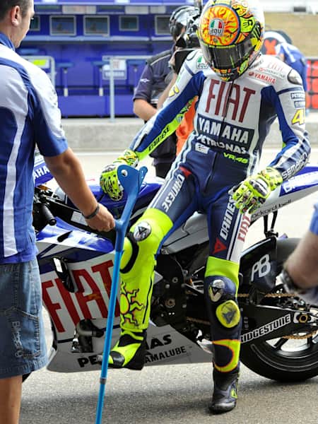 Valentino Rossi collects his crutches off the bike