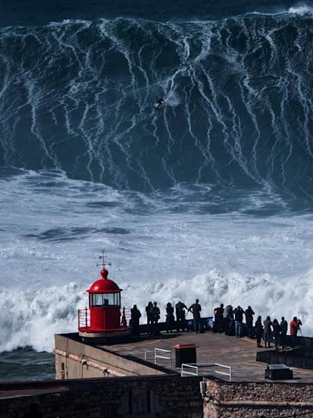 Um surfista dropa uma onda gigante em Nazaré, Portugal