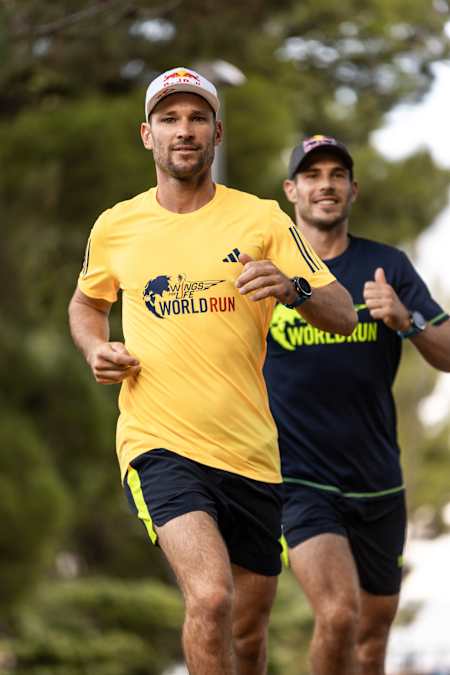 Two men running wearing Wings for Life World Run t-shirts