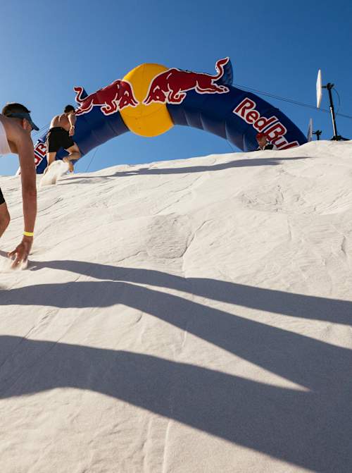 A competitor powers uphill through the sand at Red Bull Dune Dusters 2026, held at Atlantis Dunes in Cape Town, South Africa, under the iconic Red Bull archway