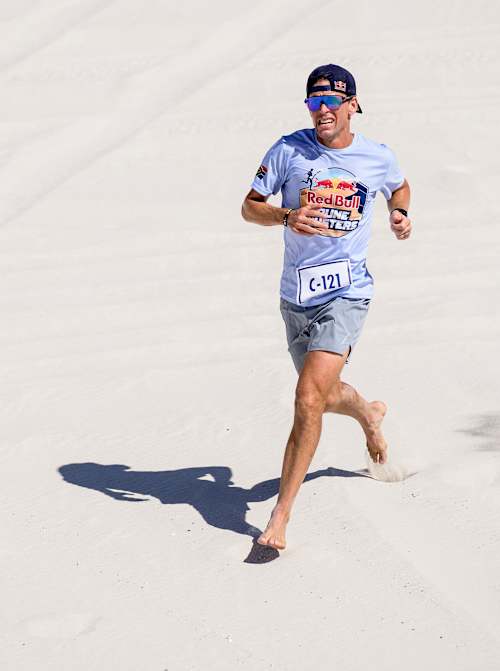 Ultra-runner Ryan Sandes sprints barefoot on the dunes during Red Bull Dune Dusters 2026 at Atlantis Dunes, Cape Town, South Africa, showcasing peak adventure and endurance