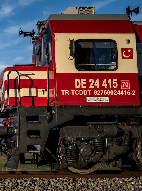 Red Bull yarış giysileri içindeki Dario Costa, Şubat 2026'da Afyonkarahisar'da hareket halindeki bir trenden yapılacak tarihi ilk iniş ve kalkış öncesinde bir Türk kargo treninin yanında duruyor