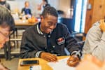 Marketing graduate taking part in the Red Bull graduate program at one of the key locations across Europe and writing something on a piece of paper while smiling