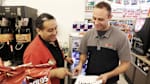 Red Bull account manager building relationships and talking to the store manager in a store in front of a Red Bull refrigerator