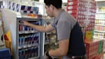 Red Bull account sales manager putting Red Bull cans in the refrigerator in a store and discovering new sales opportunities thanks to power selling