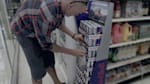Red Bull account sales manager attaches a promotional sign between Red Bull pallets in a store